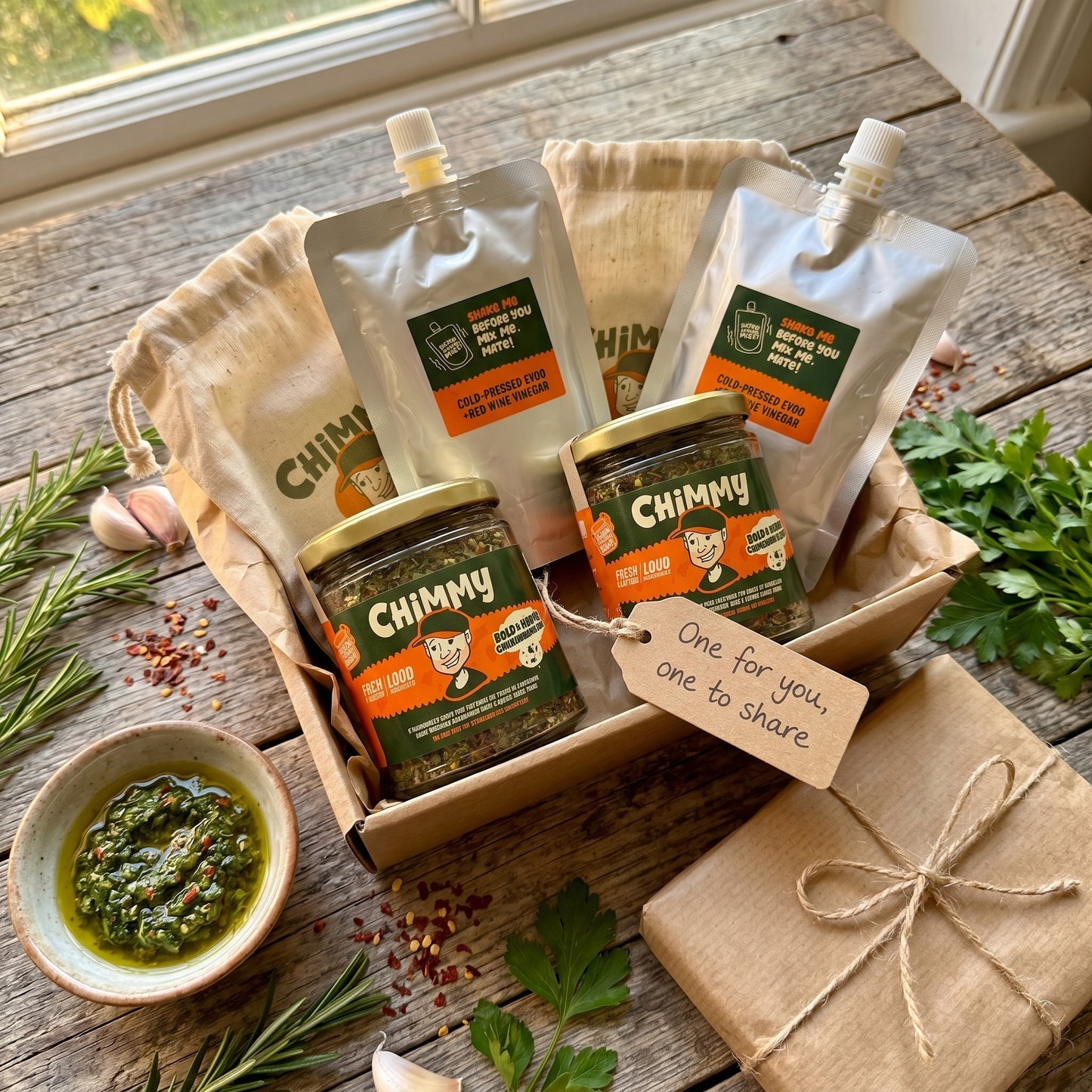 Double Drizzle gift duo — two Chimmy chimichurri kits (two herb jars and two cold-pressed EVOO + red wine vinegar pouches) in a kraft gift box with a tag reading One for you, one to share, fresh rosemary, parsley, garlic and a bowl of mixed chimichurri
