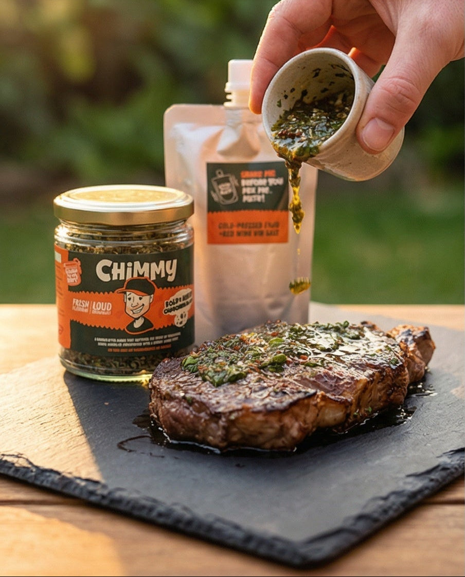 Hand pouring fresh Chimmy chimichurri sauce over a grilled steak, with the Chimmy herb jar and vinegar pouch in the background